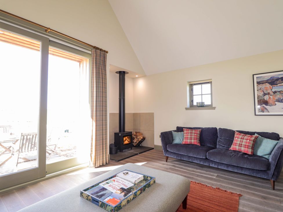 A living room with a sofa and a stove at The Mandrel in Portmahomack