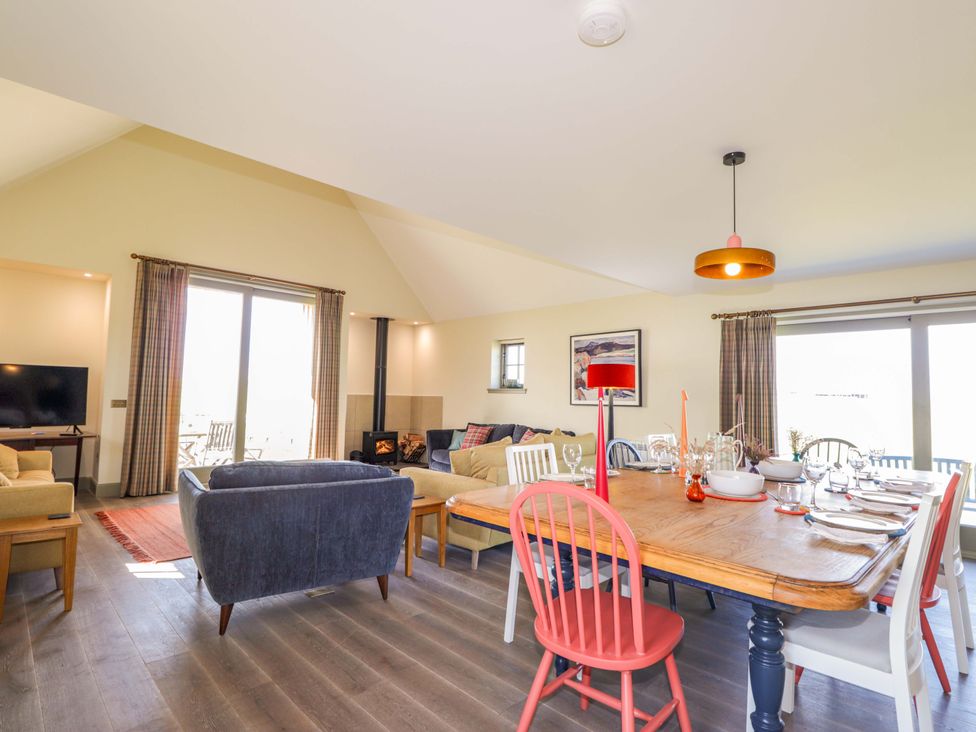 A dining room with a table set for dinner and a sofa at The Mandrel in Portmahomack