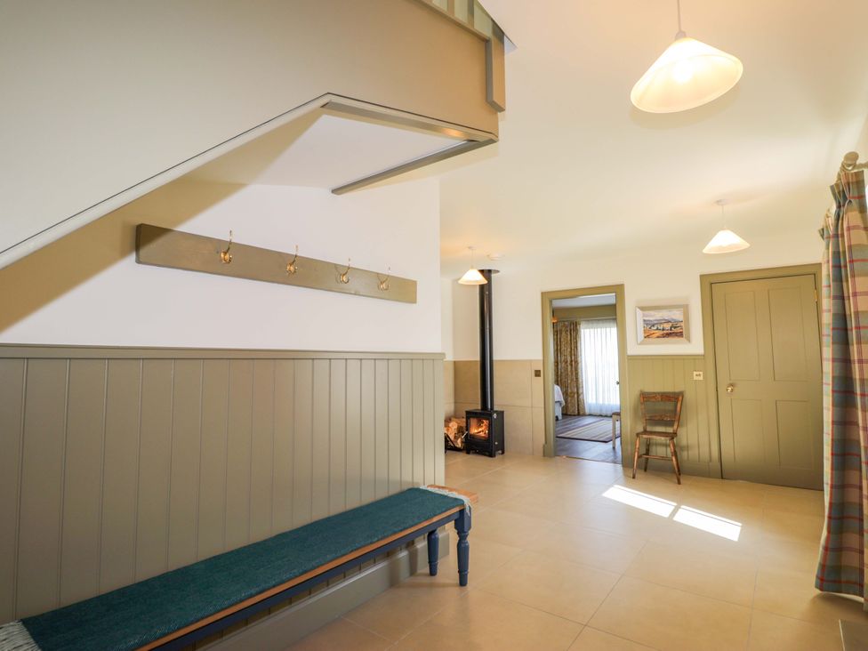 A hallway with a bench and staircase at The Mandrel in Portmahomack