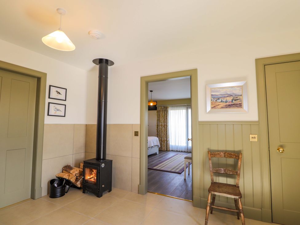 A hallway with fireplace and chair at The Mandrel in Portmahomack