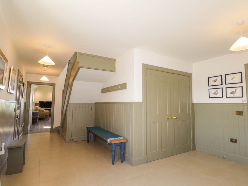 A hallway with a bench and staircase at The Mandrel in Portmahomack