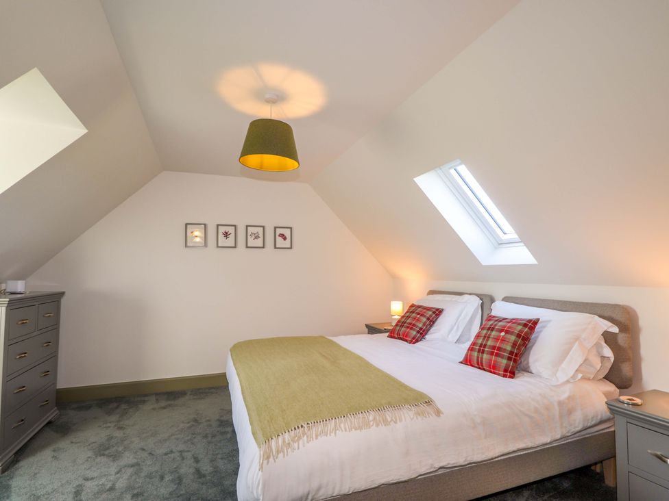 A bedroom with a bed and framed pictures at The Mandrel in Portmahomack