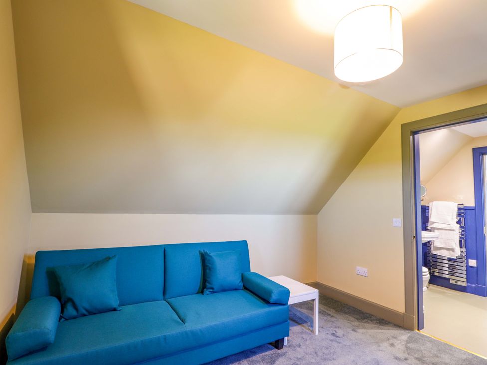 A bedroom with a blue sofa and table at The Mandrel in Portmahomack