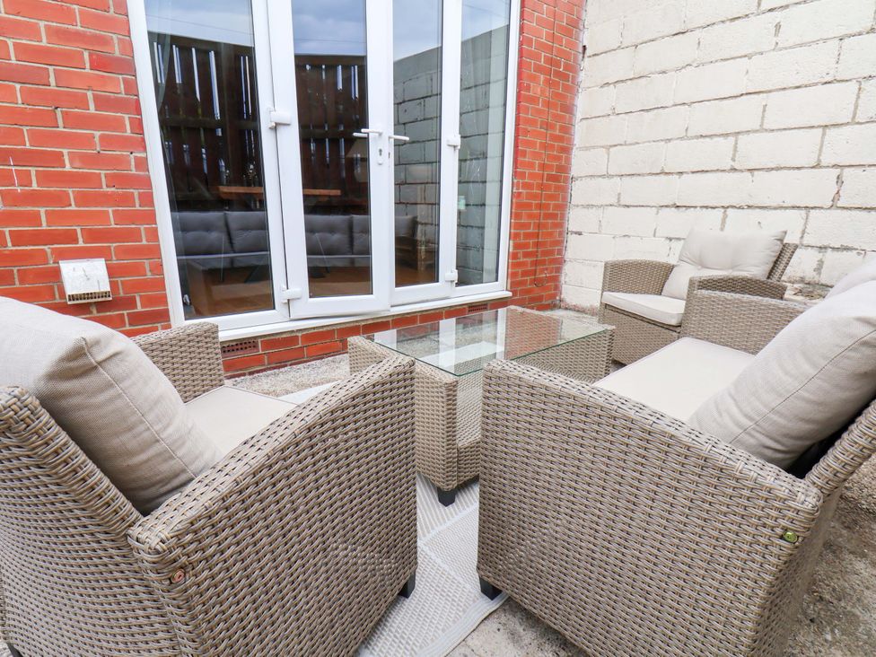 A patio area with four chairs and a glass table at Falcon's Nest in Whitby
