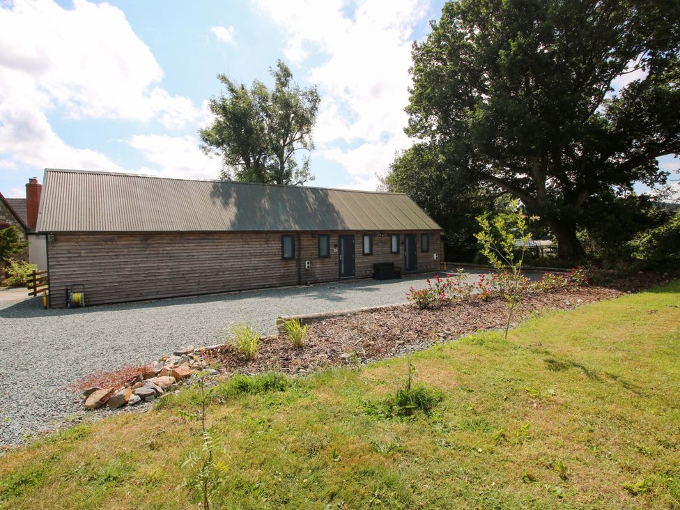 An exterior view of a wooden building surrounded by gravel and garden at Stiper View Barn 1 in Gravels Bank