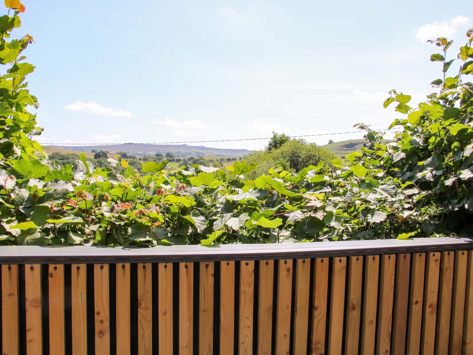 A view of greenery and hills from a wooden railing at Stiper View Barn 2 Gravels Bank