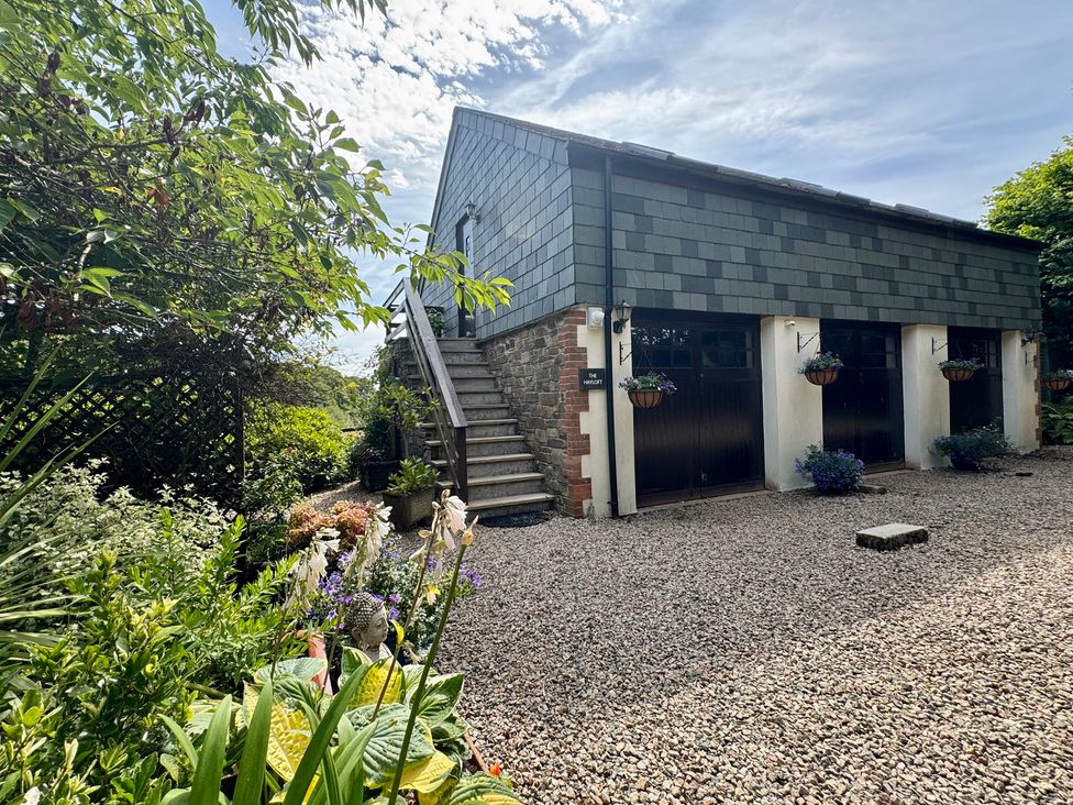 A garden view with steps leading to a building at The Hayloft in Lostwithiel