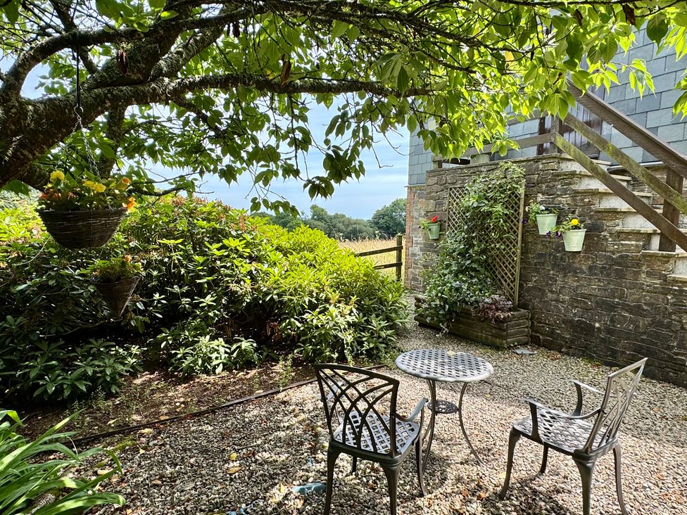 A garden with a table and chairs under a tree at The Hayloft in Lostwithiel