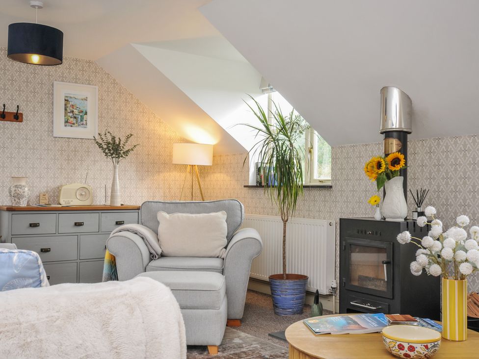 A living room with a chair and table at The Hayloft in Lostwithiel