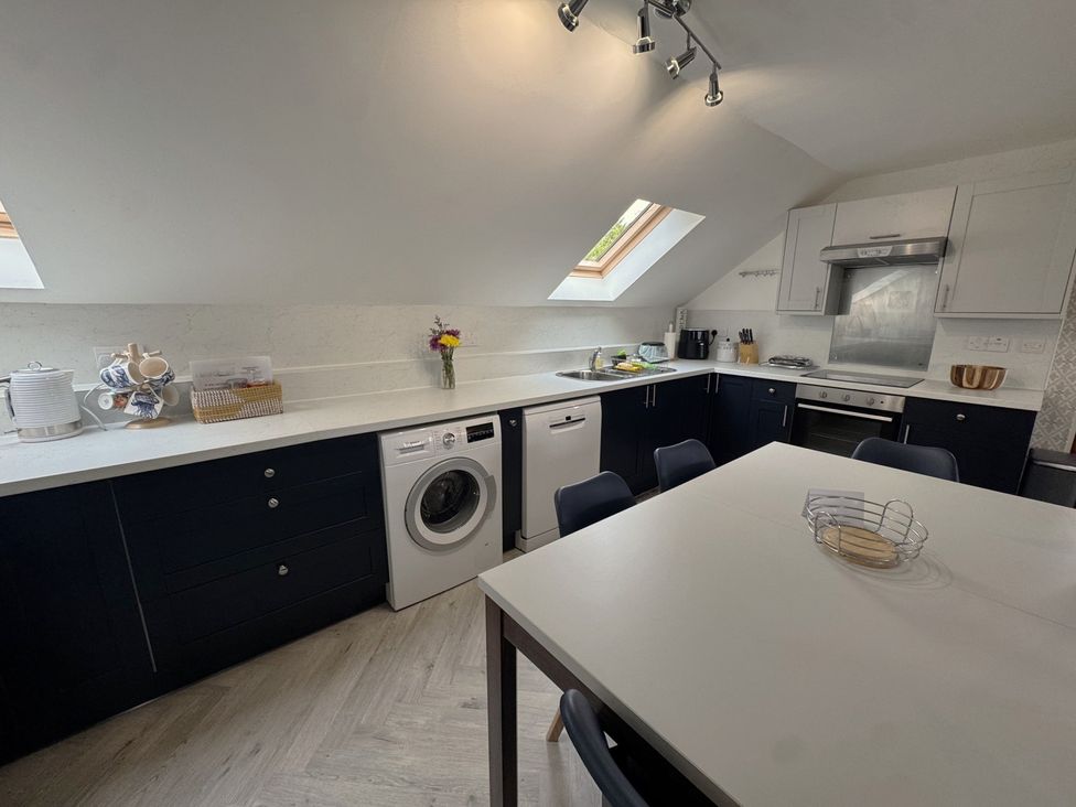 A kitchen with a washing machine and a table at The Hayloft in Lostwithiel
