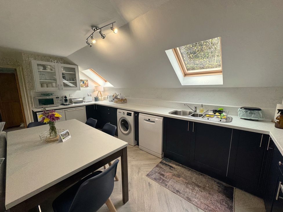 A kitchen with appliances and a dining table at The Hayloft in Lostwithiel
