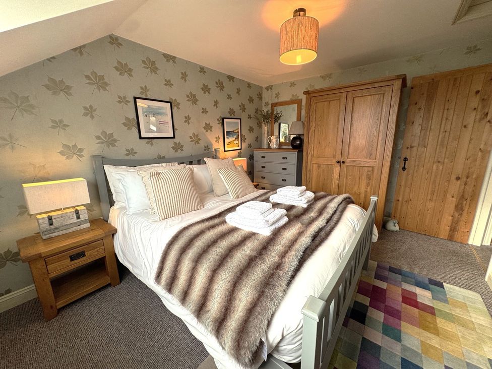 A bedroom with a bed, lamp, closet, and wall decorations at The Hayloft in Lostwithiel