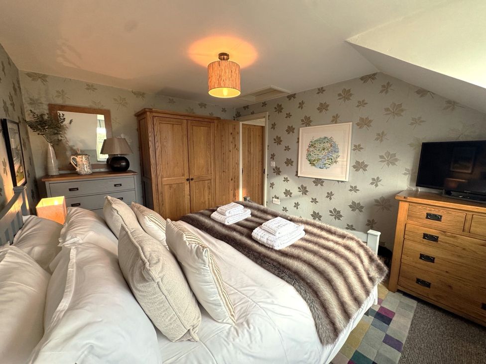 A bedroom with a bed and wardrobe at The Hayloft in Lostwithiel