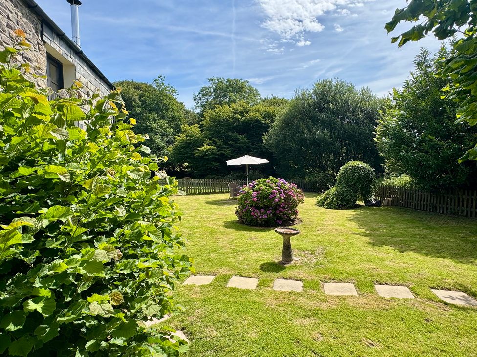 A garden with a flower bed and umbrella at The Mill in Lostwithiel