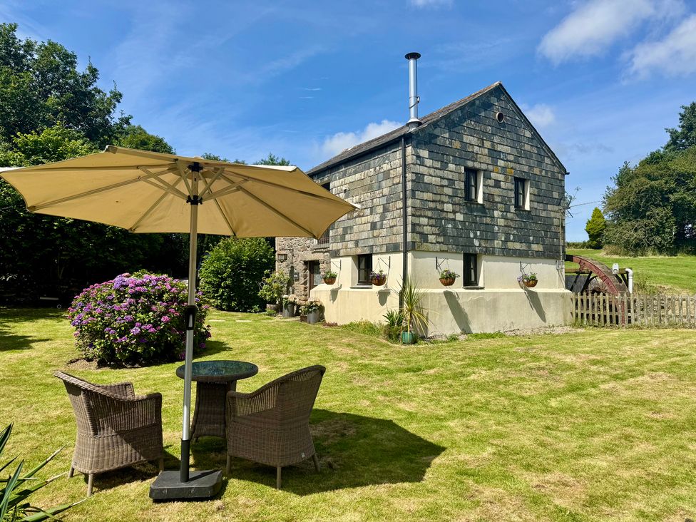 A garden with a table and chairs under an umbrella at The Mill in Lostwithiel