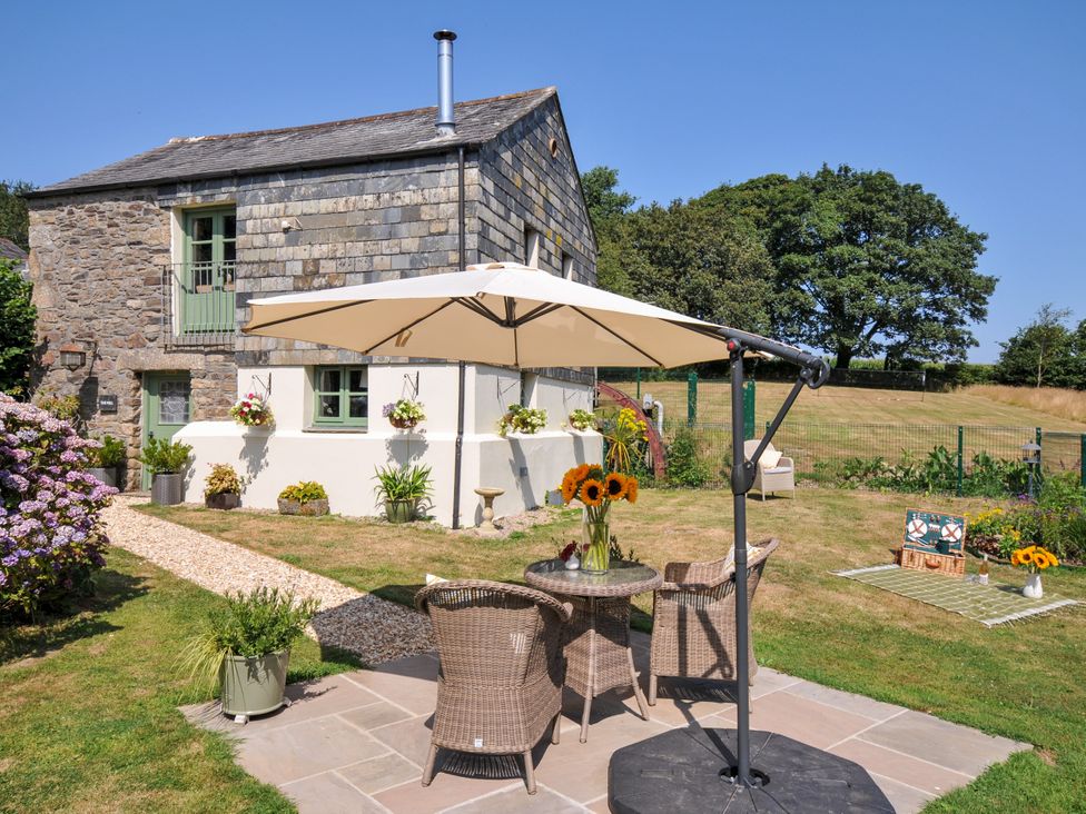 An outdoor space with a table and chairs under an umbrella at The Mill in Lostwithiel