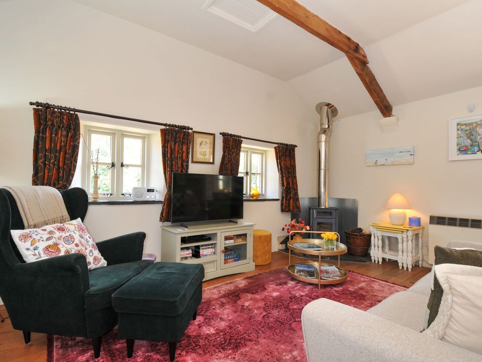 A living room with an armchair and television at The Mill in Lostwithiel