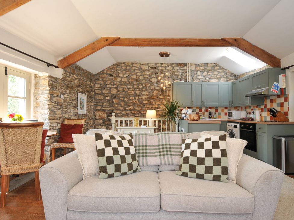 A living room with a sofa and kitchen area at The Mill in Lostwithiel