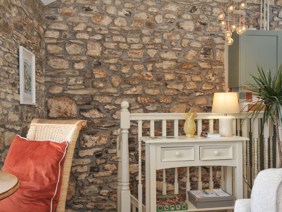 A living room with a stone wall and a side table at The Mill in Lostwithiel