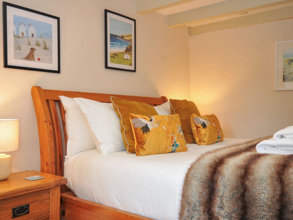 A bedroom with a wooden bed and wall art at The Mill in Lostwithiel