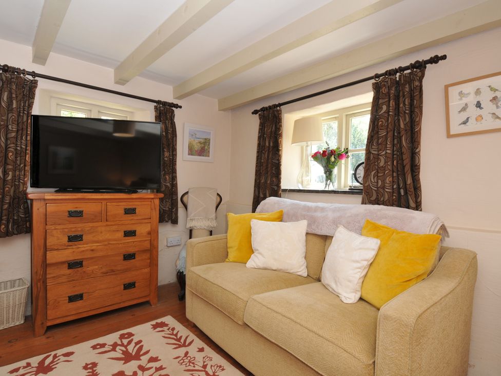 A living room with a television and a sofa at The Mill in Lostwithiel