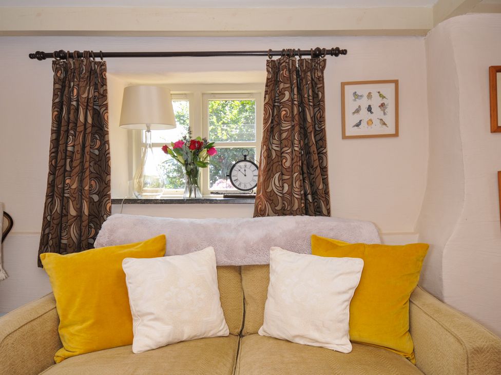 A living room with a window, lamp, and flowers at The Mill in Lostwithiel