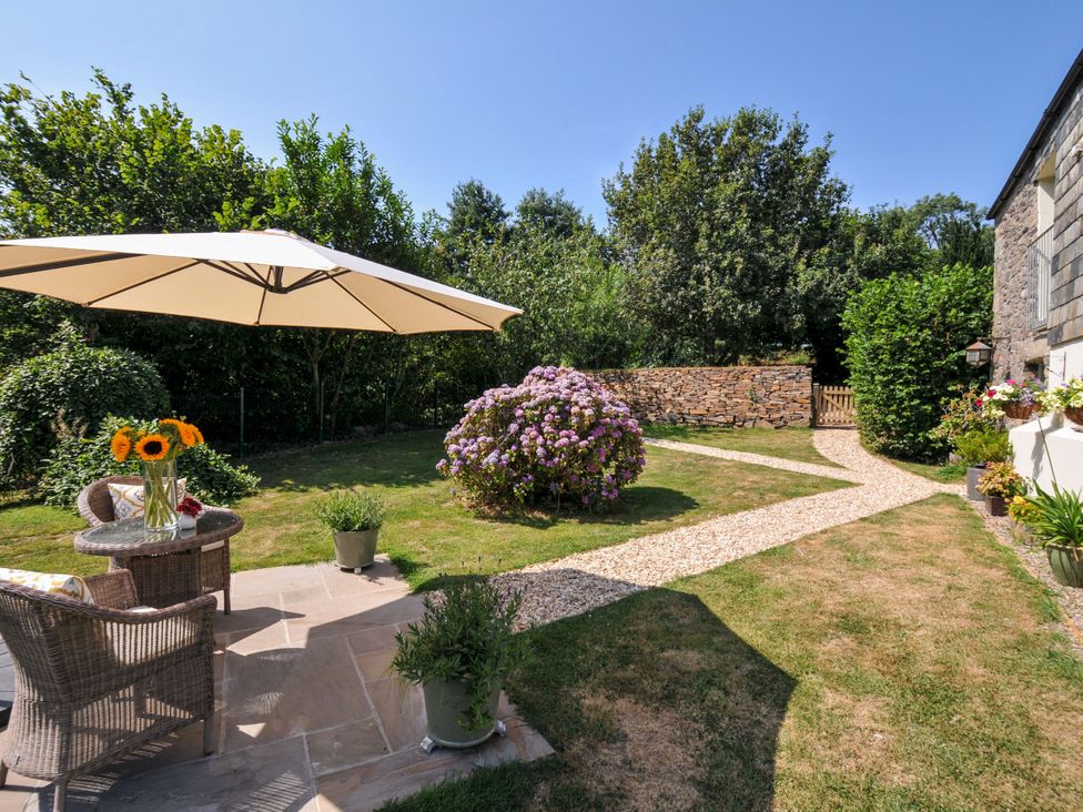 A garden with a table and chairs under an umbrella at The Mill in Lostwithiel