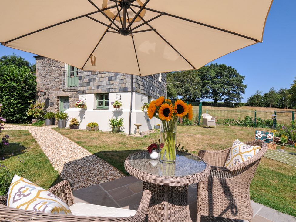 A garden with a table and chairs under an umbrella at The Mill in Lostwithiel