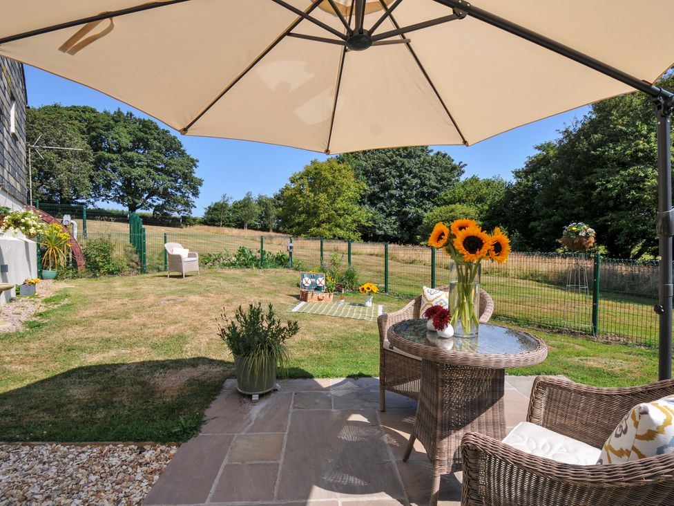 An outdoor area with a table, chairs, and sunflowers at The Mill in Lostwithiel