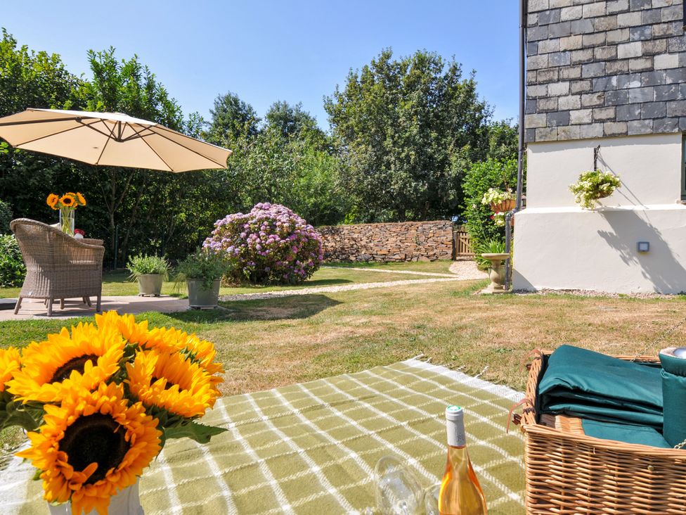 A garden with sunflowers, an umbrella, and a chair at The Mill in Lostwithiel