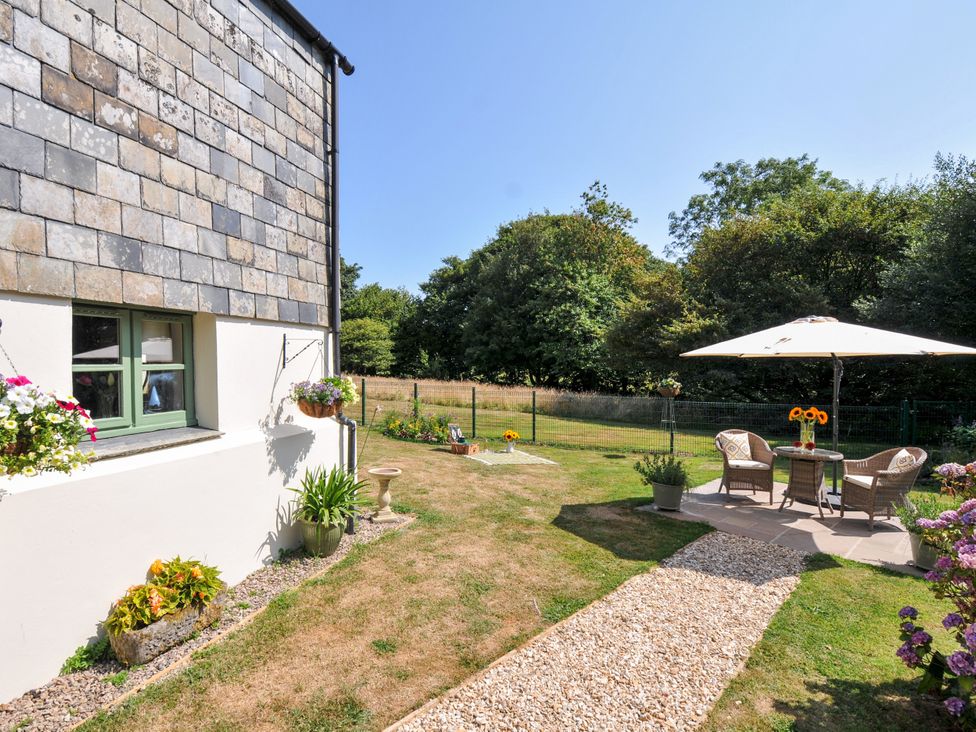 A garden with a table and chairs under an umbrella at The Mill in Lostwithiel