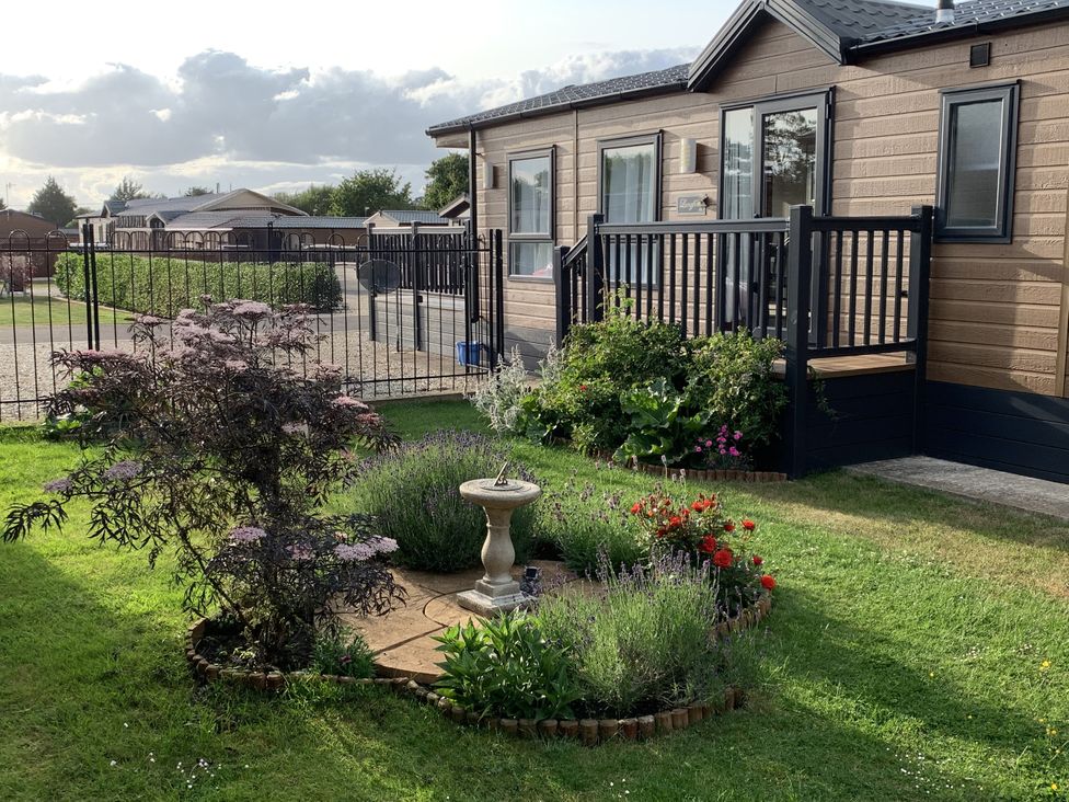 A garden with a flowerbed and decking at Longdon Lodge Wickhamford near Evesham