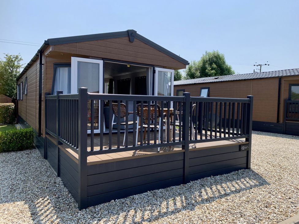A holiday home with a deck and railing at Longdon Lodge in Wickhamford near Evesham