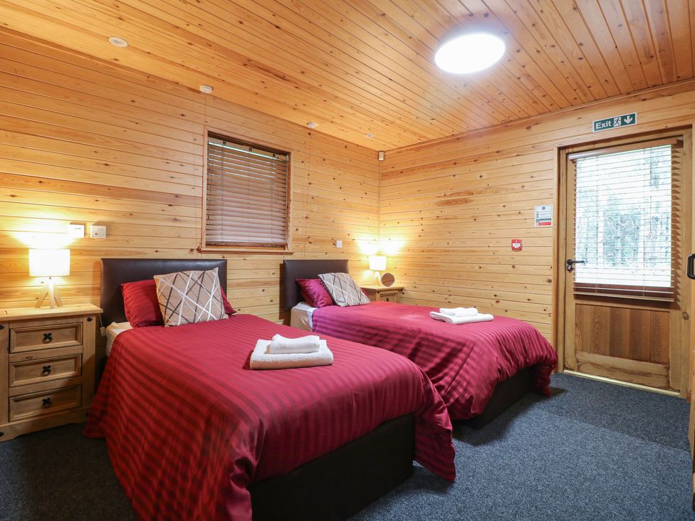 A bedroom with two single beds and wooden walls at Rowan Lodge in Rosliston