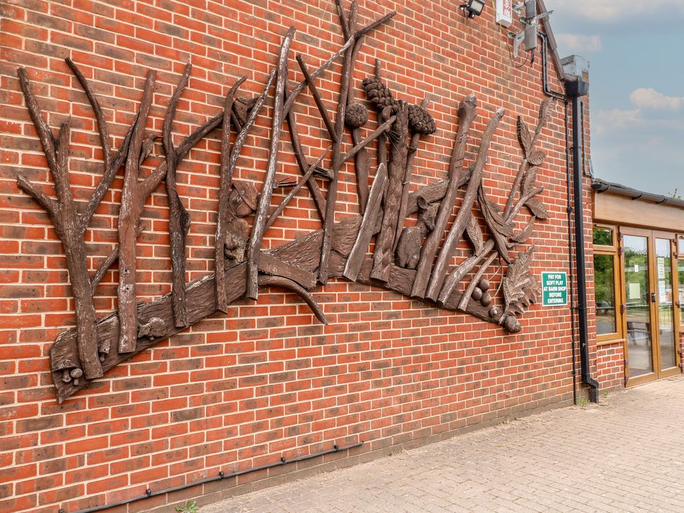 A brick wall with a large wooden art installation of trees and pinecones at Rowan Lodge in Rosliston