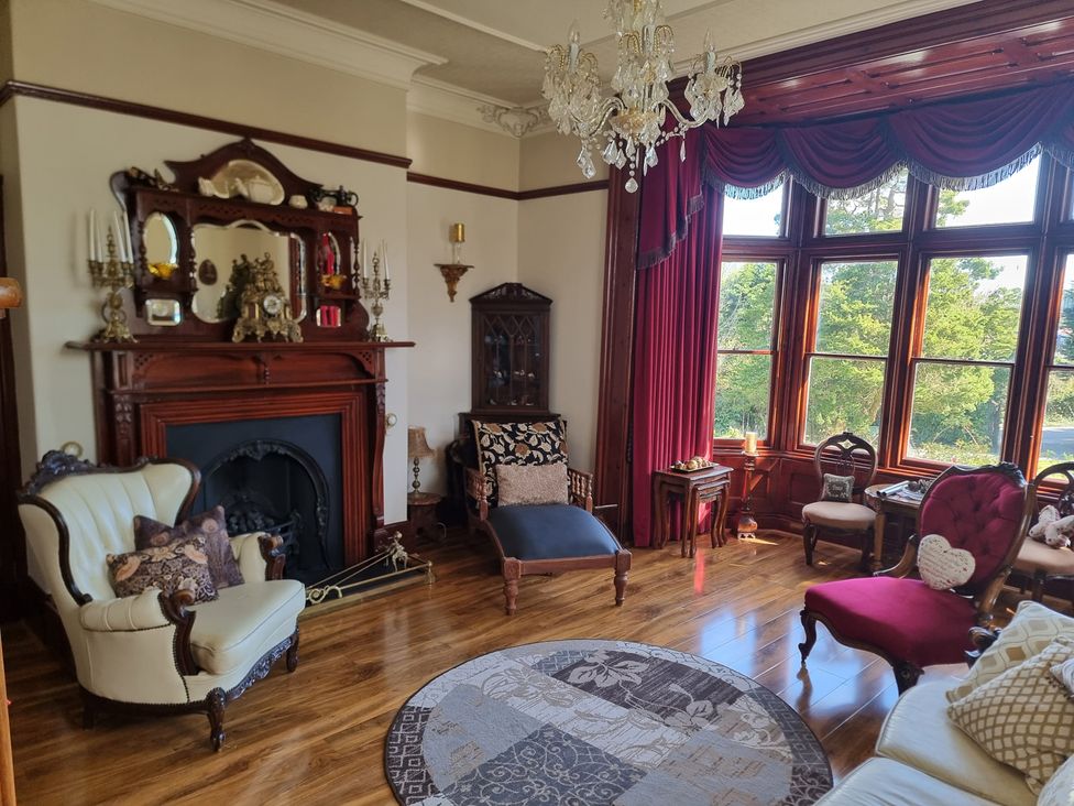 A living room with a fireplace and large windows at Ashleigh House