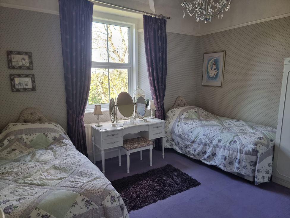 A bedroom with two beds and a dressing table at Ashleigh House