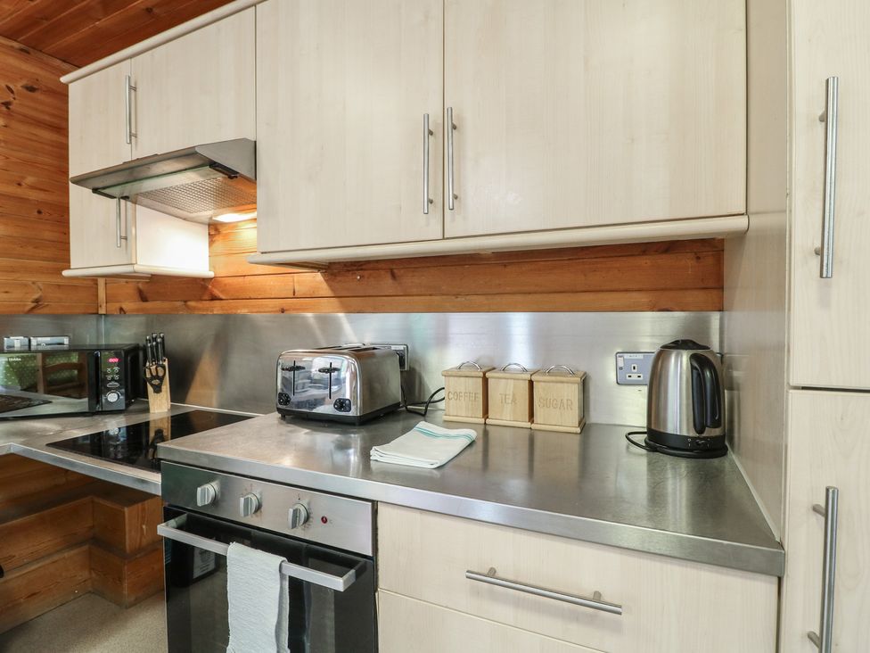 A kitchen counter with a toaster kettle microwave knife block and storage containers at Oak Lodge in Rosliston