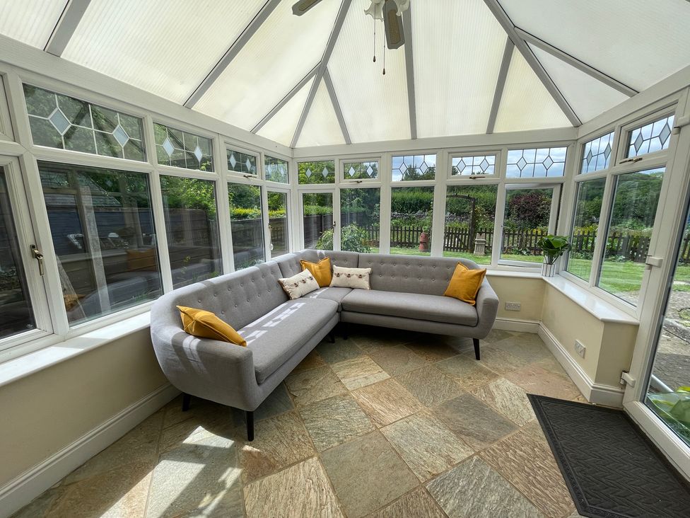 A conservatory with a grey sofa and large windows at Montclair