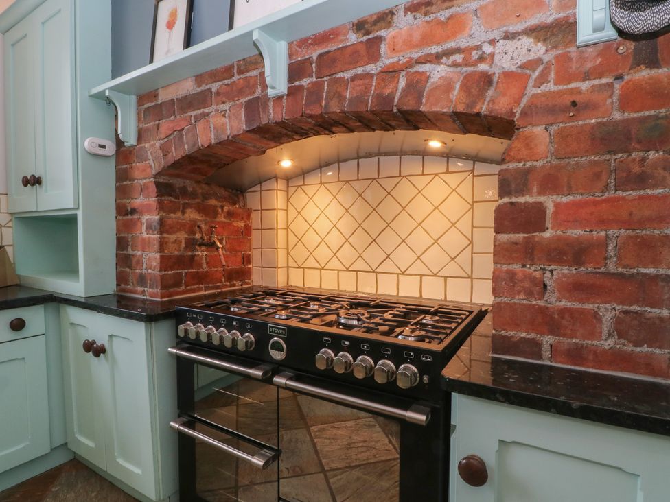 A kitchen with a gas stove and brick wall at Montclair in Buxton