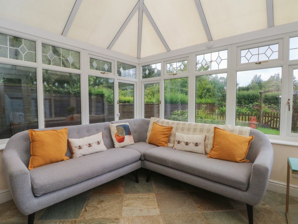 A conservatory with a sofa and cushions at Montclair in Buxton