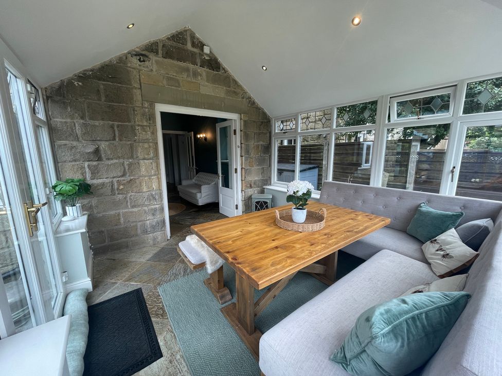 A conservatory with a wooden table and benches at Montclair in Buxton