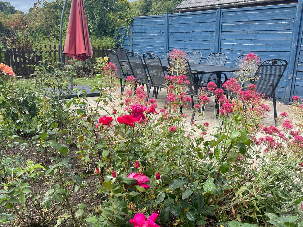 A garden with a table and chairs surrounded by flowers at Montclair in Buxton