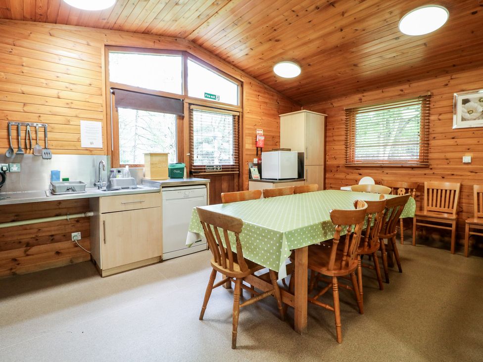 A kitchen dining area with a table covered by a green polka dot tablecloth and wooden chairs at Chestnut Lodge in Rosliston