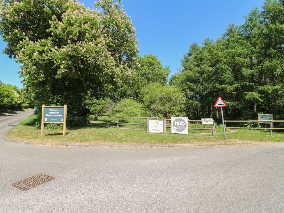 An outdoor area with signs for Rosliston Forestry Centre and a cafe surrounded by trees at Chestnut Lodge in Rosliston