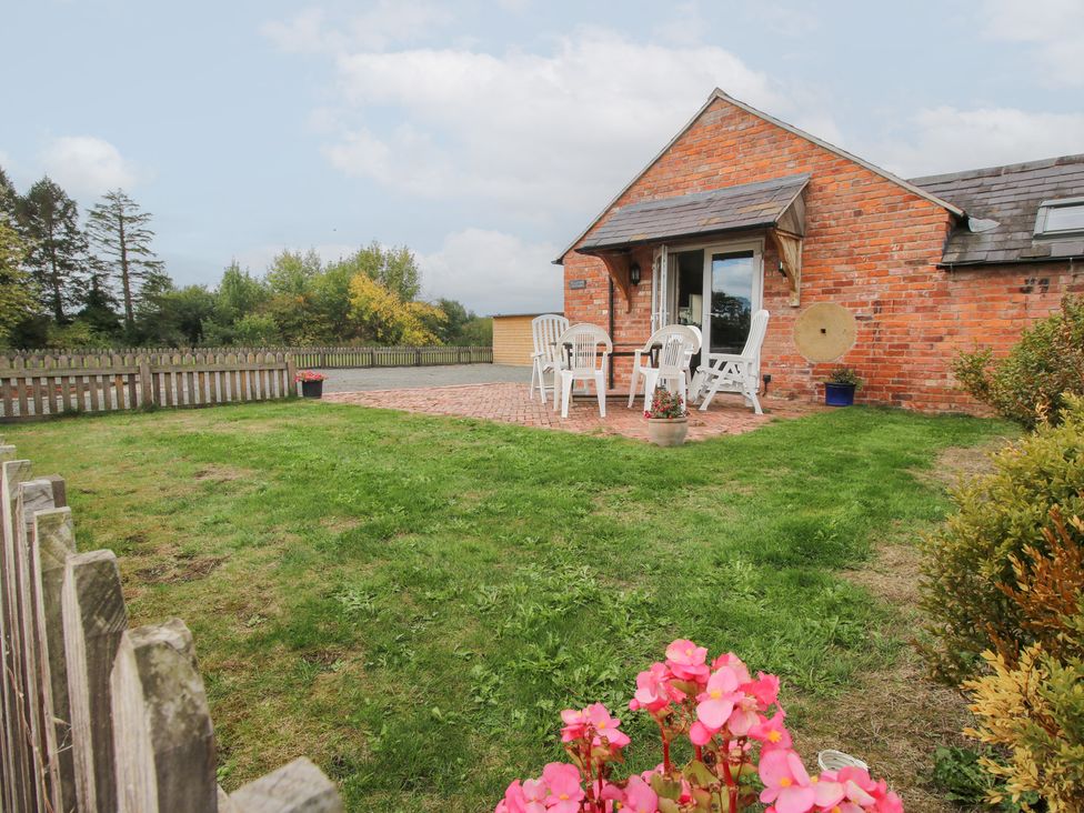 A garden with patio furniture and flowers at Millstone Cottages - Millstone Cottage in Westbury