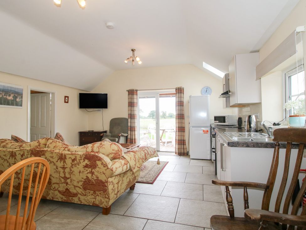 A living room with a sofa and kitchen appliances at Millstone Cottages - Millstone Cottage in Westbury