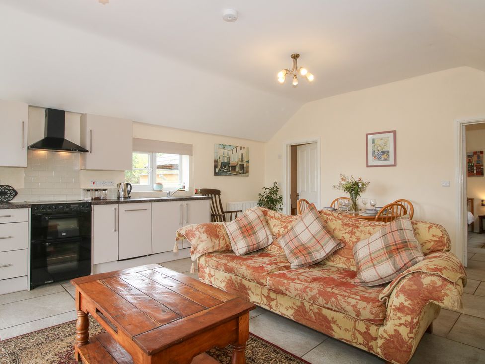A living room with a sofa and kitchen unit at Millstone Cottages - Millstone Cottage in Westbury