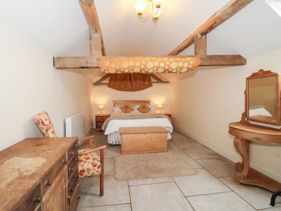 A bedroom with a bed and furniture at Millstone Cottages - Millstone Cottage Westbury