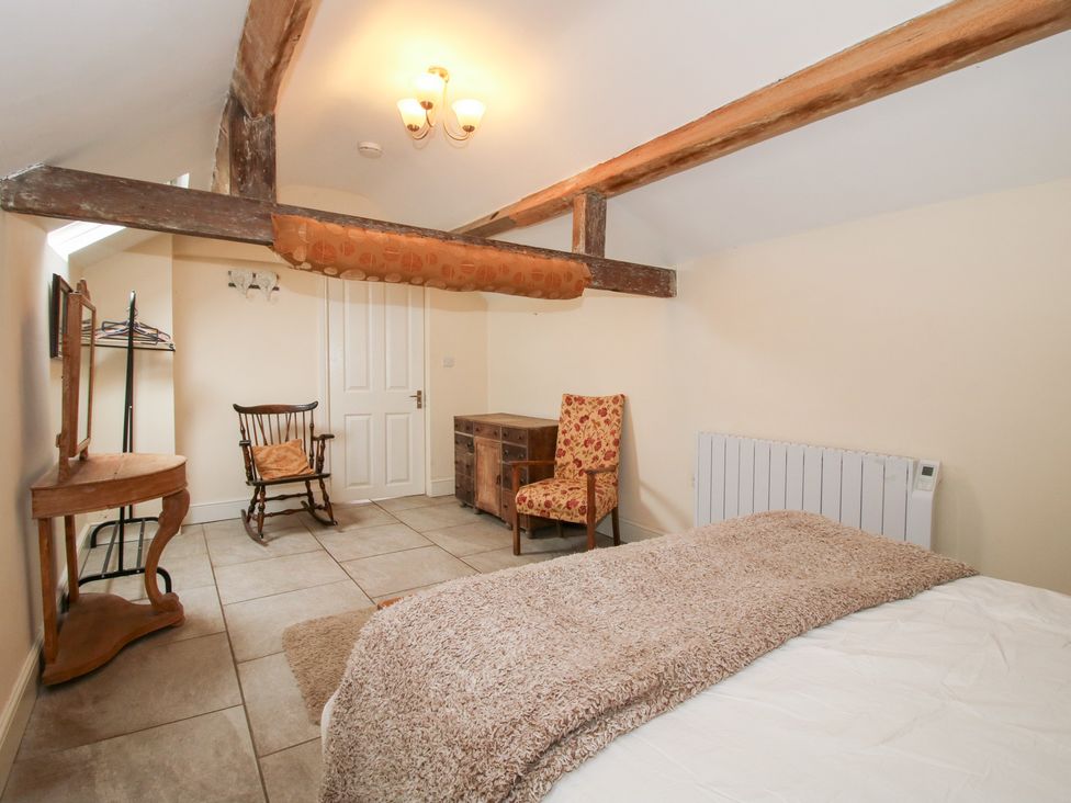 A bedroom with a bed and chairs at Millstone Cottages - Millstone Cottage in Westbury